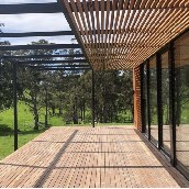 Custom timber deck and slatted pergola by Crafted Edge Construct overlooking a peaceful rural landscape.